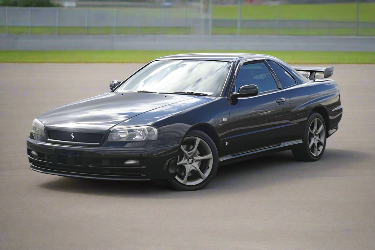 Black R34 Series 2 Coupe parked in carpark with fence behind